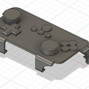 May include: A grey 3D-printed game controller stand. The stand has a rectangular base with raised buttons, including a directional pad, circular buttons, and a four-button cluster. The stand has curved legs for support.