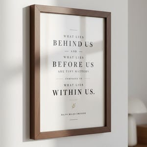 May include: A framed print with a brown wooden frame. The print features the quote "What lies behind us and what lies before us are tiny matters compared to what lies within us." by Ralph Waldo Emerson, in a minimalist design.