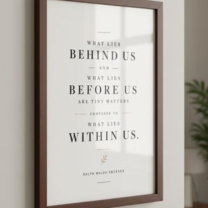 May include: A framed print with a dark brown wooden frame. The print features the quote "What Lies Behind Us and What Lies Before Us Are Tiny Matters Compared to What Lies Within Us" by Ralph Waldo Emerson, in black text.