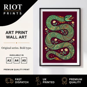 May include: A framed art print featuring a green, patterned snake with orange accents on a deep maroon background. The snake is surrounded by small yellow flowers and stars. The text reads RIOT PRINTS, ART PRINT WALL ART, Original series. Bold type.