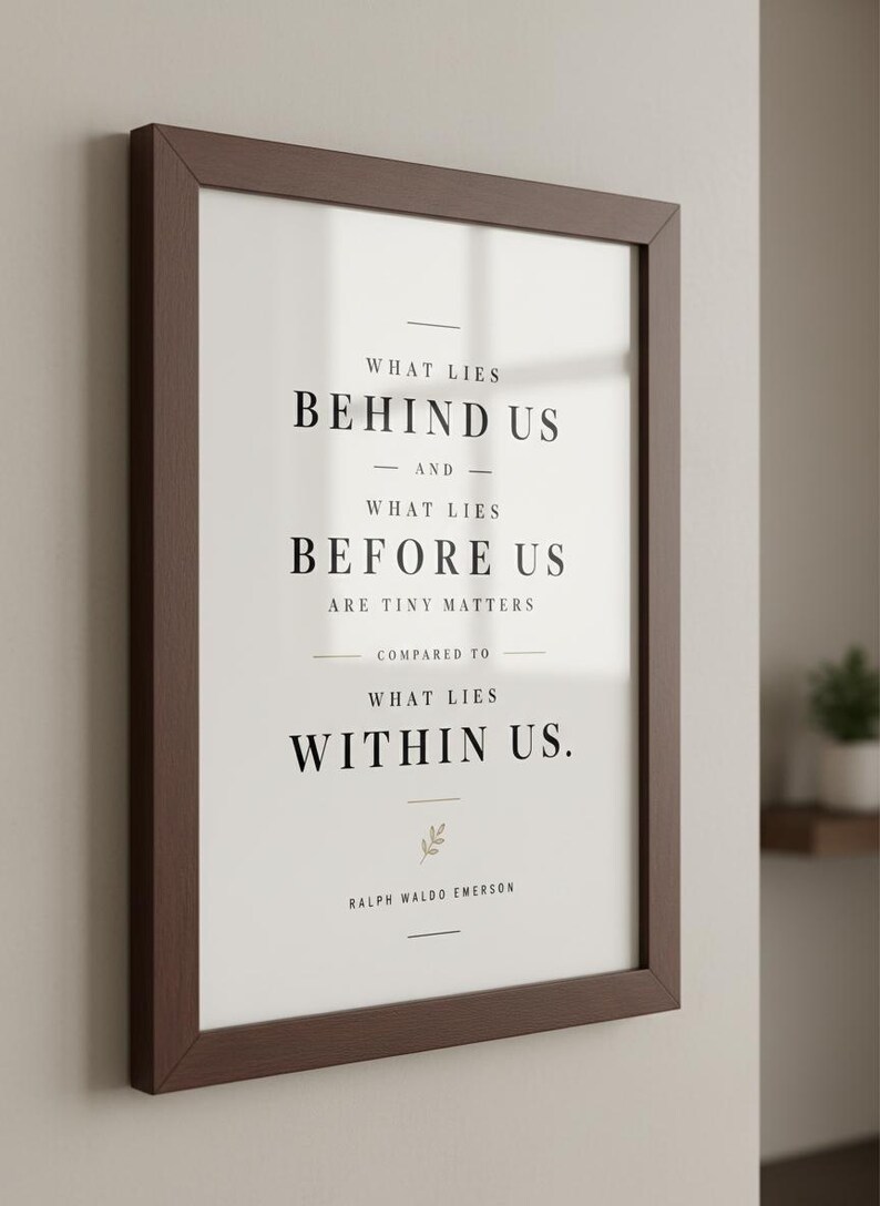 May include: A framed print with a dark brown wooden frame. The print features the quote "WHAT LIES BEHIND US AND WHAT LIES BEFORE US ARE TINY MATTERS COMPARED TO WHAT LIES WITHIN US." by Ralph Waldo Emerson, in black text.