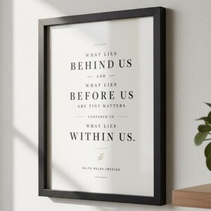 May include: A framed print with a black wooden frame. The print features the quote "What lies behind us and what lies before us are tiny matters compared to what lies within us." by Ralph Waldo Emerson, in a minimalist style.
