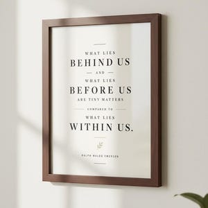 May include: A framed print with a dark brown wooden frame. The print features the quote "What lies behind us and what lies before us are tiny matters compared to what lies within us." by Ralph Waldo Emerson.
