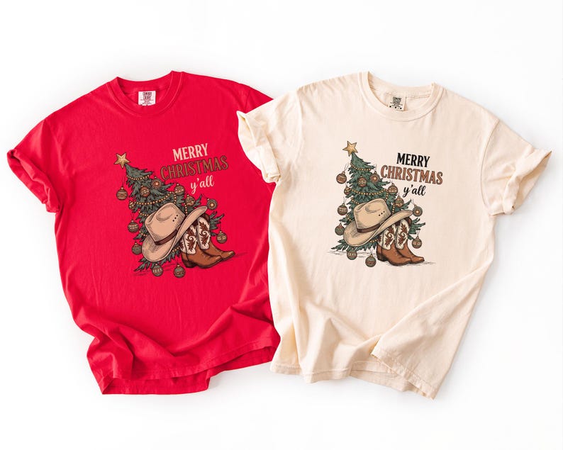 May include: Two t-shirts, one red and one cream, with a festive Christmas design. The design features a Christmas tree, cowboy hat, and boots, and the text "Merry Christmas y'all".