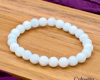 May include: A stretch bracelet composed of round, polished, semi-translucent white beads. The beads have a smooth, reflective surface and are strung together in a circular loop. The text Celestia Crystal Jewellery is visible in the bottom right corner.