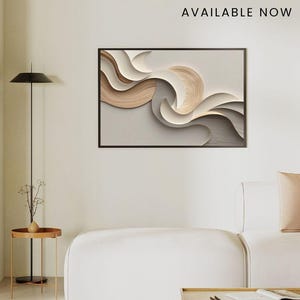 Op de afbeelding: Een ingelijst abstract kunstwerk met gelaagde, vloeiende vormen in tinten beige, crème en bruin. Het kunstwerk staat tegen een lichtgrijze achtergrond. De tekst "New Design AVAILABLE NOW" staat boven het kunstwerk.