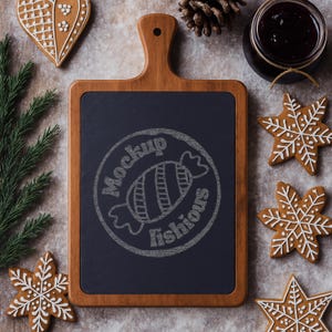 May include: A wooden cutting board with a dark blue center, featuring a chalk drawing of a candy and the words "Mockup fishious". Decorated with gingerbread cookies, a jar of jam, pine needles, and a pine cone.