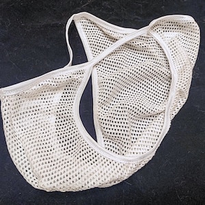 Könnte beinhalten: Weiße Netz-Unterwäsche mit zartem, spitzem Besatz. Die Unterwäsche ist in der Hälfte gefaltet und zeigt das komplizierte Netz-Muster.