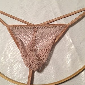 May include: A pair of pink mesh underwear with thin straps. The underwear is made of a delicate, see-through material.