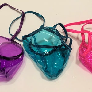 以下が含まれることがあります： 異なる色のトリムが付いた透明な下着が3組。下着は紫、ターコイズ、ピンクです。