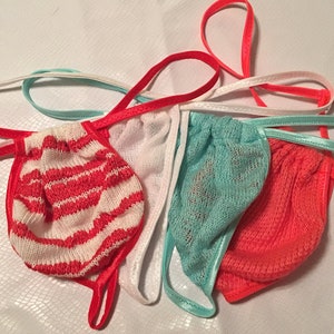 May include: Four pairs of colorful string bikini bottoms. The bottoms are made of a soft, stretchy material and have a variety of patterns, including stripes, polka dots, and floral prints.