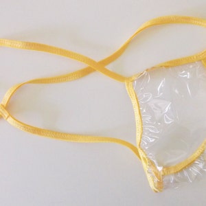 以下が含まれることがあります： 黄色いゴムバンドが付いた透明なプラスチック製のTバック