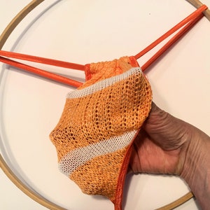 May include: Orange and white striped crocheted lingerie with thin orange straps.