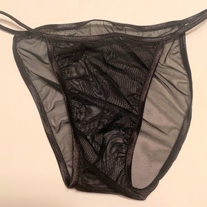 May include: Black sheer lingerie with a delicate lace trim. The lingerie has a low-cut design and a thin strap.