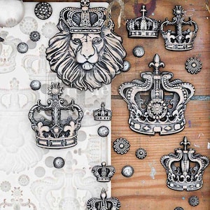 May include: A white silicone mold with multiple crown shapes, including a lion head crown. The mold is surrounded by silver-toned metal crowns of various designs on a wooden surface.