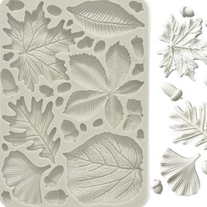 Puede incluir: Un molde de silicona con varias formas de hojas y bellotas. El molde es blanco y tiene una superficie texturizada.