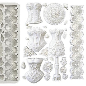 Puede incluir: Molde de silicona blanco con múltiples diseños de encaje, rosas y corsés. El molde es para hacer decoraciones de pasteles.