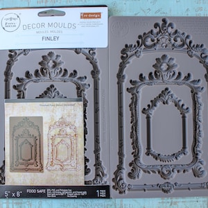May include: Gray silicone molds with ornate frame designs. The package reads "FINLEY" and "DECOR MOULDS". The mold measures 5" x 8". The package also shows a finished piece. The molds are food safe.