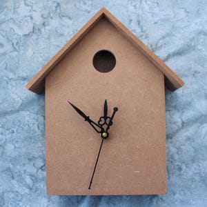 May include: A brown wooden birdhouse clock with black hands. The clock face is blank and the birdhouse has a small round hole in the front.