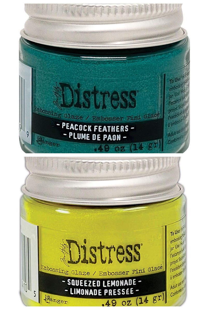 Op de afbeelding: Twee kleine potjes Distress Embossing Glaze. De bovenste pot is tealgroen en heeft het label "Peacock Feathers - Plume de Paon". De onderste pot is geel en heeft het label "Squeezed Lemonade - Limonade Press&eacute;e". Beide potjes zijn 0,49 ounce (14 gram).