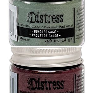 Op de afbeelding: Twee kleine potjes Distress Embossing Glaze. De bovenste pot is groen en heeft het label "Bundled Sage - Paquet de Sauge - 0,49 oz (14 g)". De onderste pot is rood en heeft het label "Aged Mahogany - Vieil &Eacute;b&egrave;ne - 0,49 oz (14 g)".