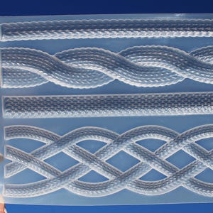 Puede incluir: Un molde de silicona transparente con cuatro diseños texturizados de cuerda y trenza. El molde se muestra sobre un fondo azul brillante, resaltando los patrones detallados para proyectos de manualidades.