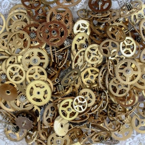 Puede incluir: Una colección de engranajes de metal dorado antiguo de varios tamaños. Los engranajes están dispuestos en un patrón aleatorio, creando un diseño visualmente interesante e intrincado.
