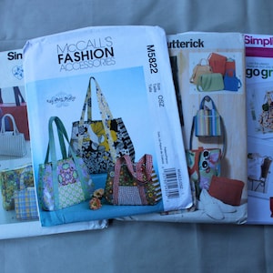 May include: Four sewing pattern envelopes for various tote bags and handbags. The envelopes feature illustrations of finished bags in floral, striped, and solid fabrics, with brand names Simplicity, McCall's Fashion Accessories, and Butterick printed on them.