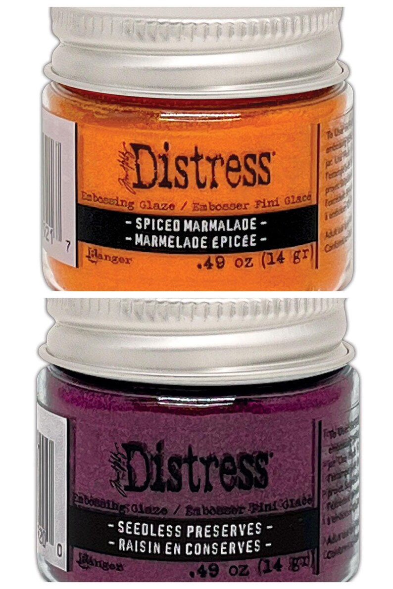 Op de afbeelding: Twee kleine potjes Distress Embossing Glaze. De bovenste pot is oranje en heeft het label "Spiced Marmalade - Marmelade &Eacute;pic&eacute;e - 0,49 oz (14 g)". De onderste pot is paars en heeft het label "Seedless Preserves - Raisin en Conserves - 0,49 oz (14 g)".