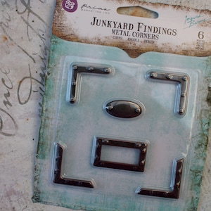 May include: A package of six metal corner embellishments for scrapbooking and crafting. The package is labeled "Junkyard Findings Metal Corners" and features a variety of corner designs.