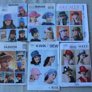 May include: A collection of six sewing pattern envelopes for various hat styles, including bucket hats, berets, and caps. The envelopes feature brand names such as Butterick, McCall's, Kwik Sew, and Vogue, displaying photographic examples of finished hats.