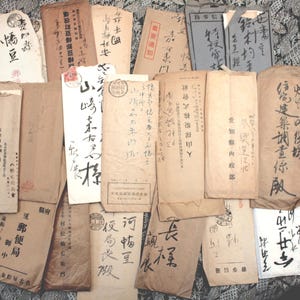 Può includere: Una collezione di documenti d'epoca in carta invecchiata con testo scritto a mano in inchiostro nero. Le carte variano per dimensioni e forma, con un mix di tonalità marrone chiaro e bianco sporco. Alcune carte presentano timbri o sigilli.