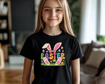 Może przedstawiać: Czarny t-shirt z kolorowym wielkanocnym wzorem. Wzór zawiera uszy królika, kokardę, pisanki i napis "EASTER" w jasnych literach. Koszulka ma krótki rękaw i okrągły dekolt.