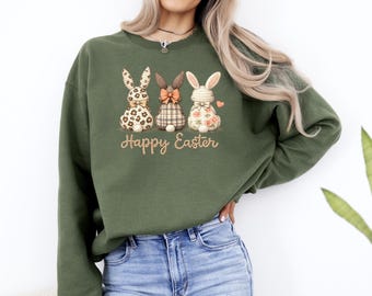 Może przedstawiać: Zielona bluza z trzema haftowanymi wzorami króliczków wielkanocnych. Króliczki mają wzory i kokardy. Słowa "Happy Easter" są wyhaftowane poniżej w złotym kolorze.