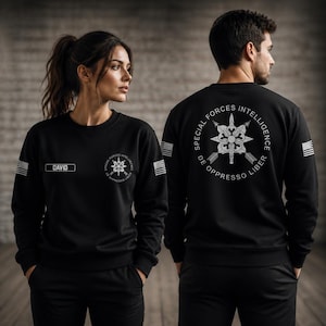 May include: A black long-sleeve sweatshirt featuring a white Special Forces Intelligence emblem with the text De Oppresso Liber on the chest and back. The sleeves display a white American flag patch, and the chest includes a name tag reading DAVID.