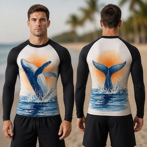 Peut inclure: Un t-shirt à manches longues raglan avec un torse blanc orné d'une illustration aquarelle d'une baleine bleue sortant de l'eau devant un soleil orange. Les manches et le dos sont noirs unis, assortis à un short de sport noir.