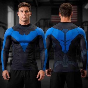May include: A long-sleeve compression shirt featuring a black and blue geometric pattern. The design includes a blue bird-like emblem on the chest and back, with black paneling extending down the sleeves and torso, creating a sleek, fitted appearance.