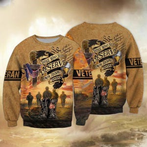 May include: A tan long-sleeve sweatshirt featuring a graphic print of soldiers, a cross with an American flag, and a bald eagle. The text reads "THOSE WHO SERVE DESERVE HONOR RESPECT THANKS" and "VETERAN". The design includes combat boots.
