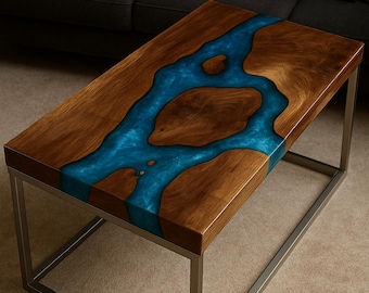 May include: A rectangular coffee table with a wooden surface and a blue resin river design. The table has a silver metal frame. The wood has a natural grain pattern. The table is approximately 48 inches long, 24 inches wide, and 16 inches high.