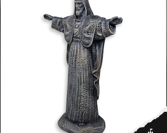 May include: A dark gray statue of a robed figure with outstretched arms. The statue has a textured surface and is mounted on a stone-like base. The figure has a beard and a hooded cloak. The statue is a religious item.