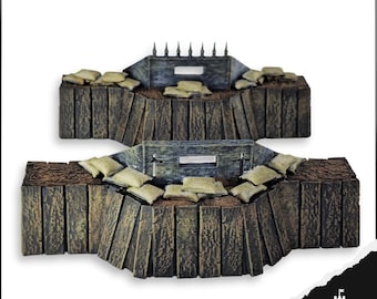 May include: Two miniature wooden fortifications with sandbags and a lookout post. The structures are made of weathered wood and feature a series of vertical planks. The sandbags are tan, and the lookout posts have a small opening. The overall design suggests a military or historical theme.