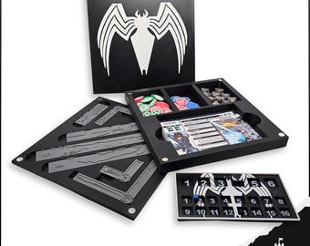 May include: A black board game organizer with a white spider symbol on the lid. The organizer includes compartments for game pieces, cards, and other components. The set also includes a game board with numbers and a logo.