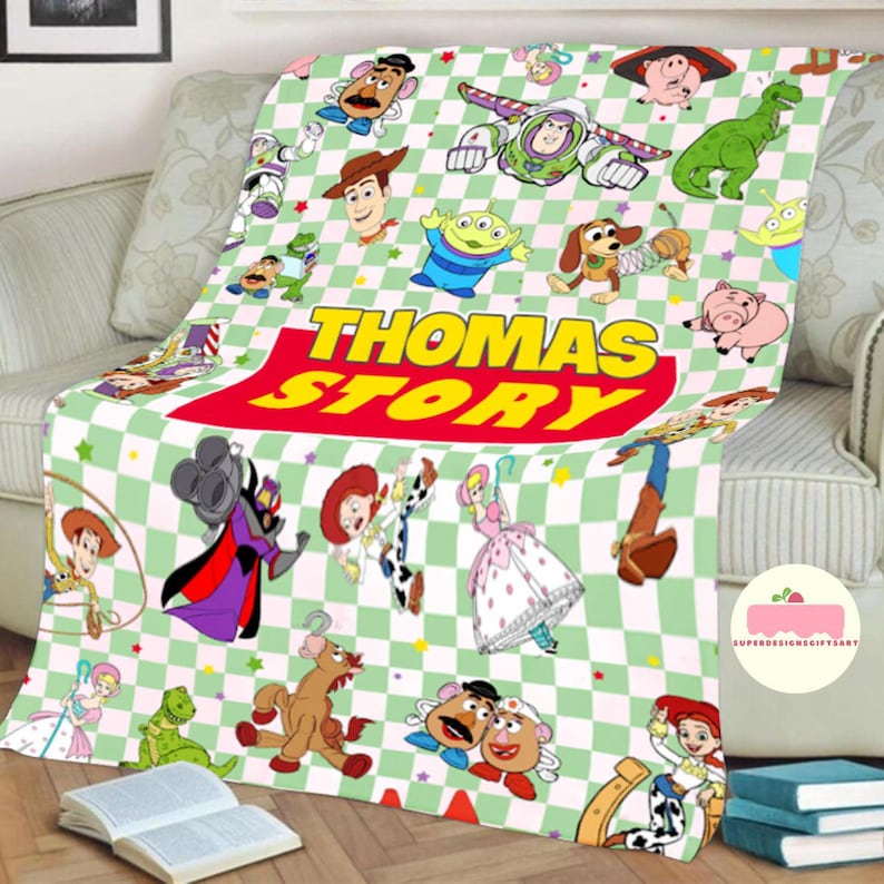 May include: A plush blanket featuring a green and white checkered pattern with various Toy Story characters. The blanket has the text "THOMAS STORY" in large, colorful letters. The blanket is draped over a sofa.