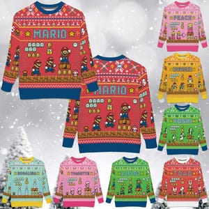 May include: Collection of colorful crew neck sweaters featuring characters from the Super Mario video game series. The sweaters have a red, pink, yellow, green, and blue base color with character graphics and text. The sweaters have blue cuffs and collars.
