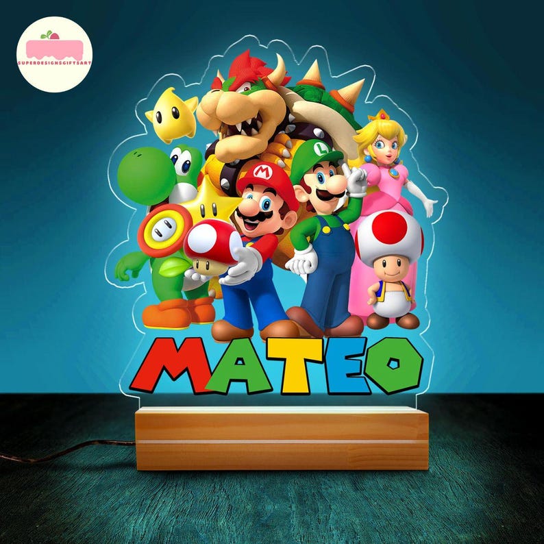Peut inclure: Une veilleuse en acrylique avec une base en bois, repr&eacute;sentant des personnages du jeu vid&eacute;o Super Mario Bros. La lumi&egrave;re affiche le nom "MATEO" en lettres color&eacute;es. Les personnages incluent Mario, Luigi et la Princesse Peach.