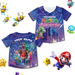 Puede incluir: Camiseta de b&eacute;isbol azul con dise&ntilde;o de "The Super Mario Galaxy". La parte delantera presenta a Yoshi y el logo del juego, mientras que la parte trasera tiene espacio para un nombre personalizado. La camiseta tiene botones y cuello blanco.