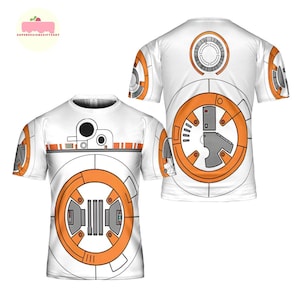 May include: White t-shirt featuring a BB-8 droid design from Star Wars. The design includes orange, gray, and black details, with the droid's circular body and mechanical components prominently displayed on the front and back of the shirt.