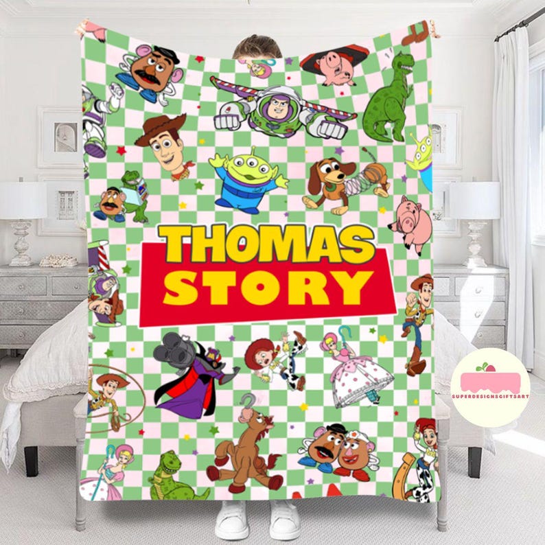 May include: A plush blanket featuring a colorful design with characters from the "Toy Story" movie. The blanket has a green and white checkered background and the text "THOMAS STORY" in yellow letters on a red rectangle.