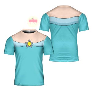 May include: A light blue t-shirt featuring a design with a beige upper section, a light blue stripe, and a star-shaped emblem with a yellow center. The shirt has short sleeves and a crew neck. The design is visible on both the front and back of the shirt.