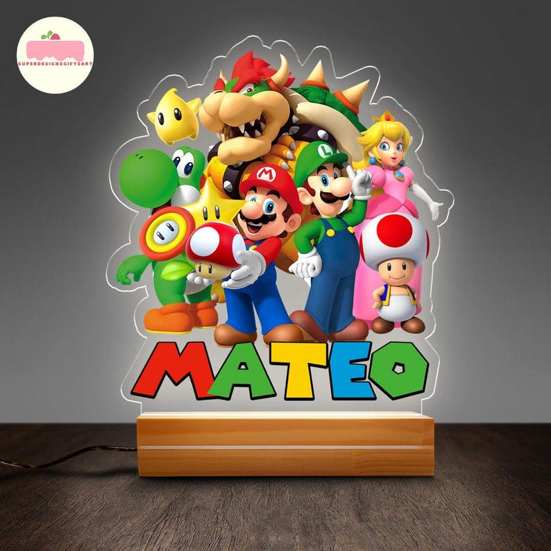 Peut inclure: Une veilleuse en acrylique color&eacute;e repr&eacute;sentant les personnages de la franchise de jeux vid&eacute;o Super Mario Bros. La lumi&egrave;re comprend Mario, Luigi, la princesse Peach et d'autres personnages, avec le nom "MATEO" en grandes lettres color&eacute;es &agrave; la base. La lumi&egrave;re repose sur une base en bois.
